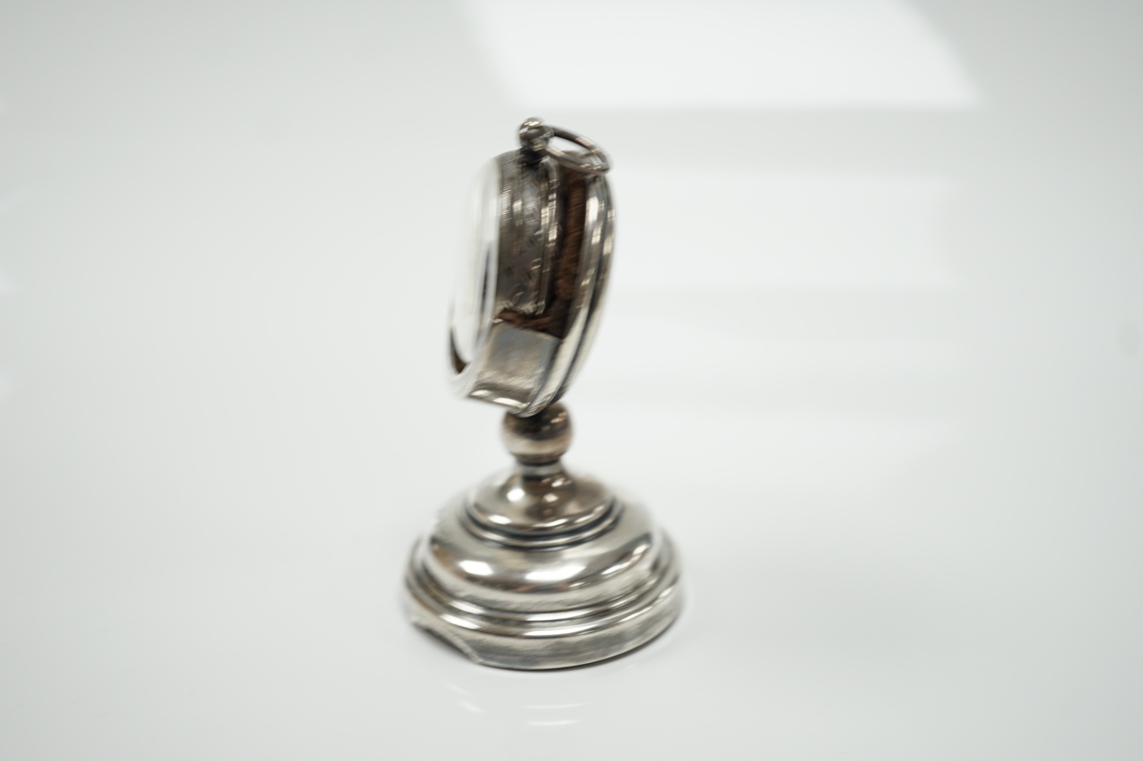 A George V silver mounted fob watch stand, Birmingham, 1923, 79mm, containing a Swiss white metal fob watch.
